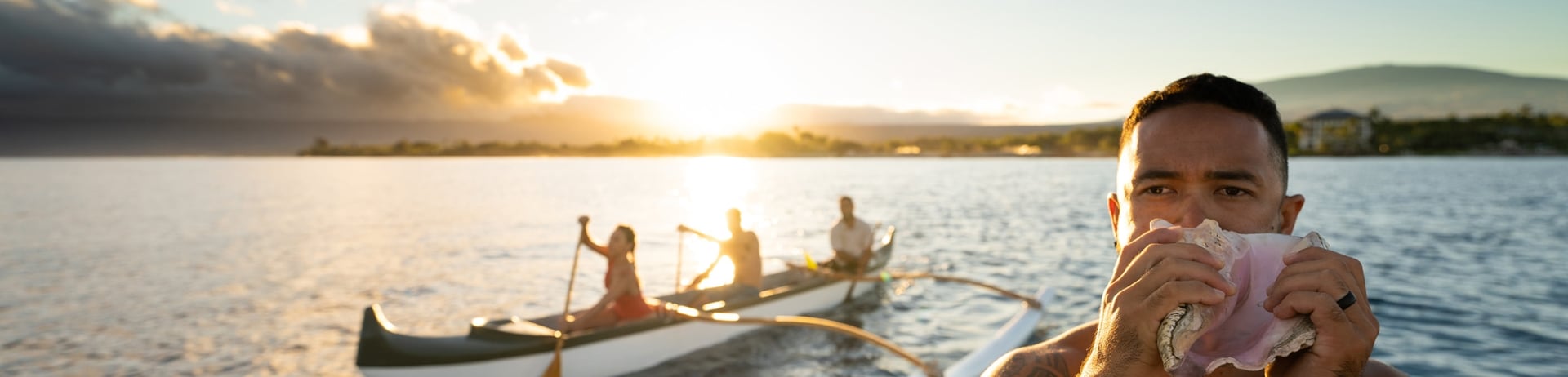 people kayaking and man blowing into a shell