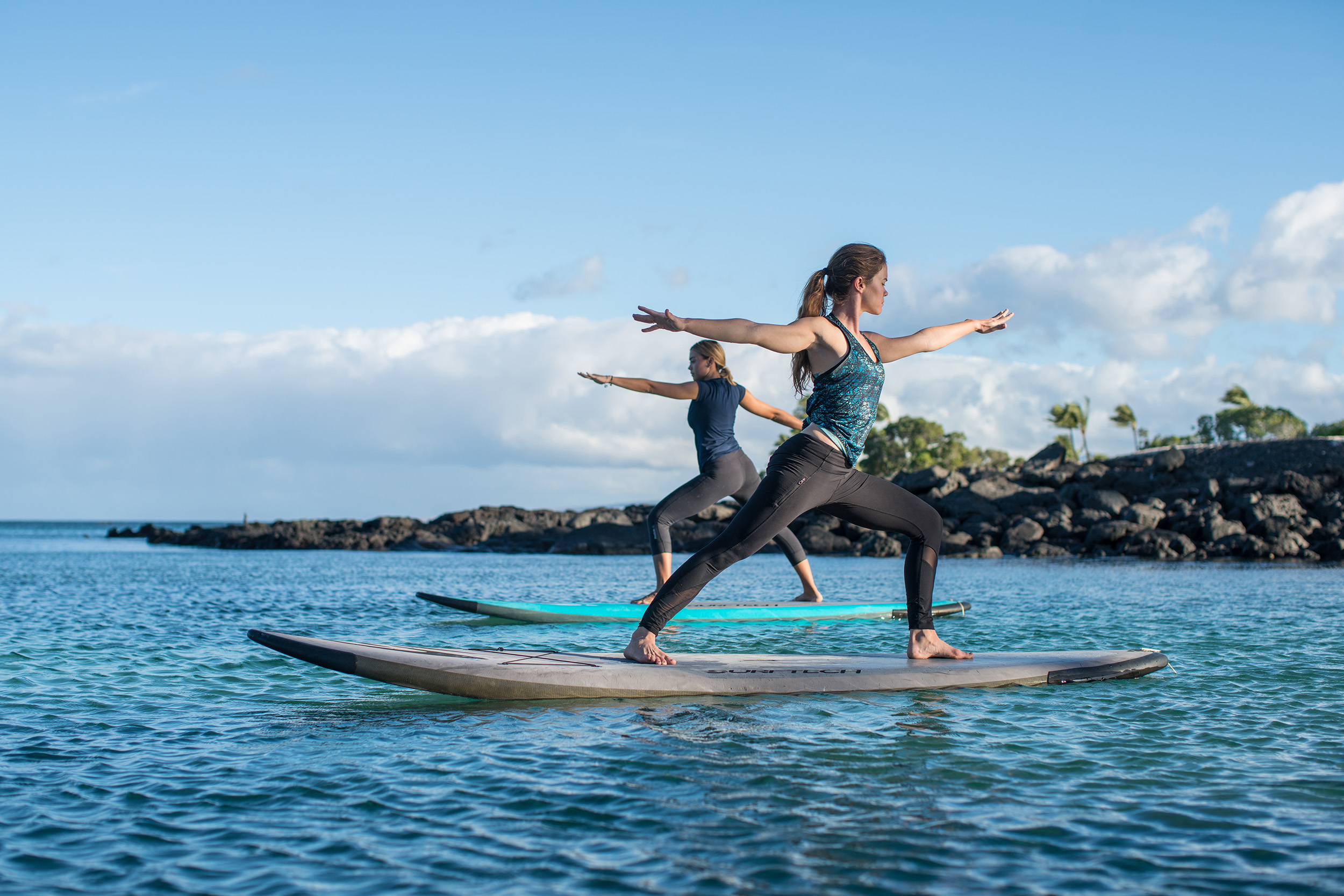two women doing yoga on paddleboards