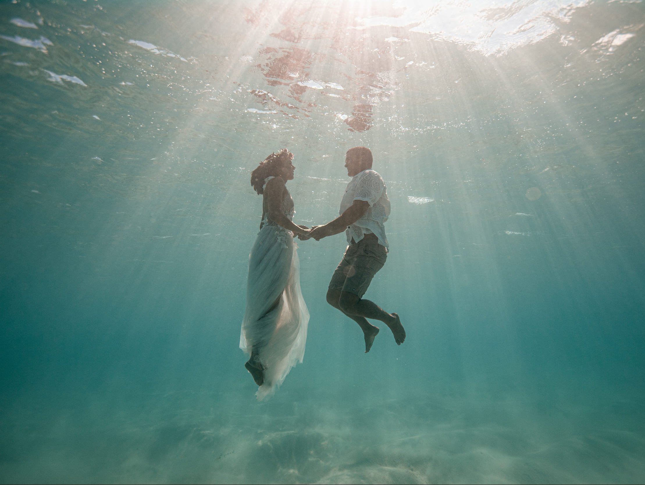 bride and groom posing underwater