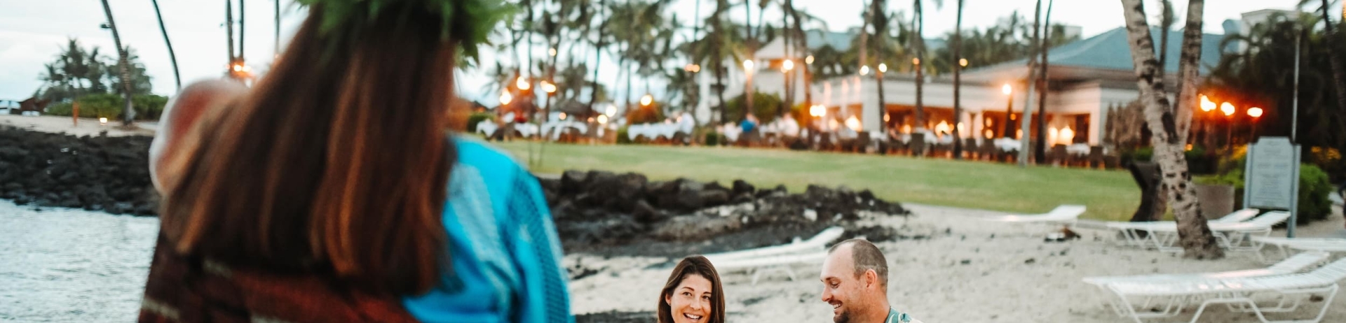 family listening to a storyteller on the beach