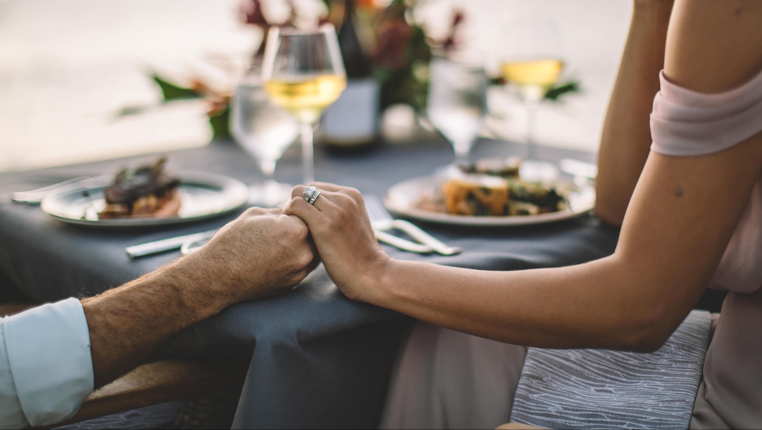a couple holding hands while eating dinner