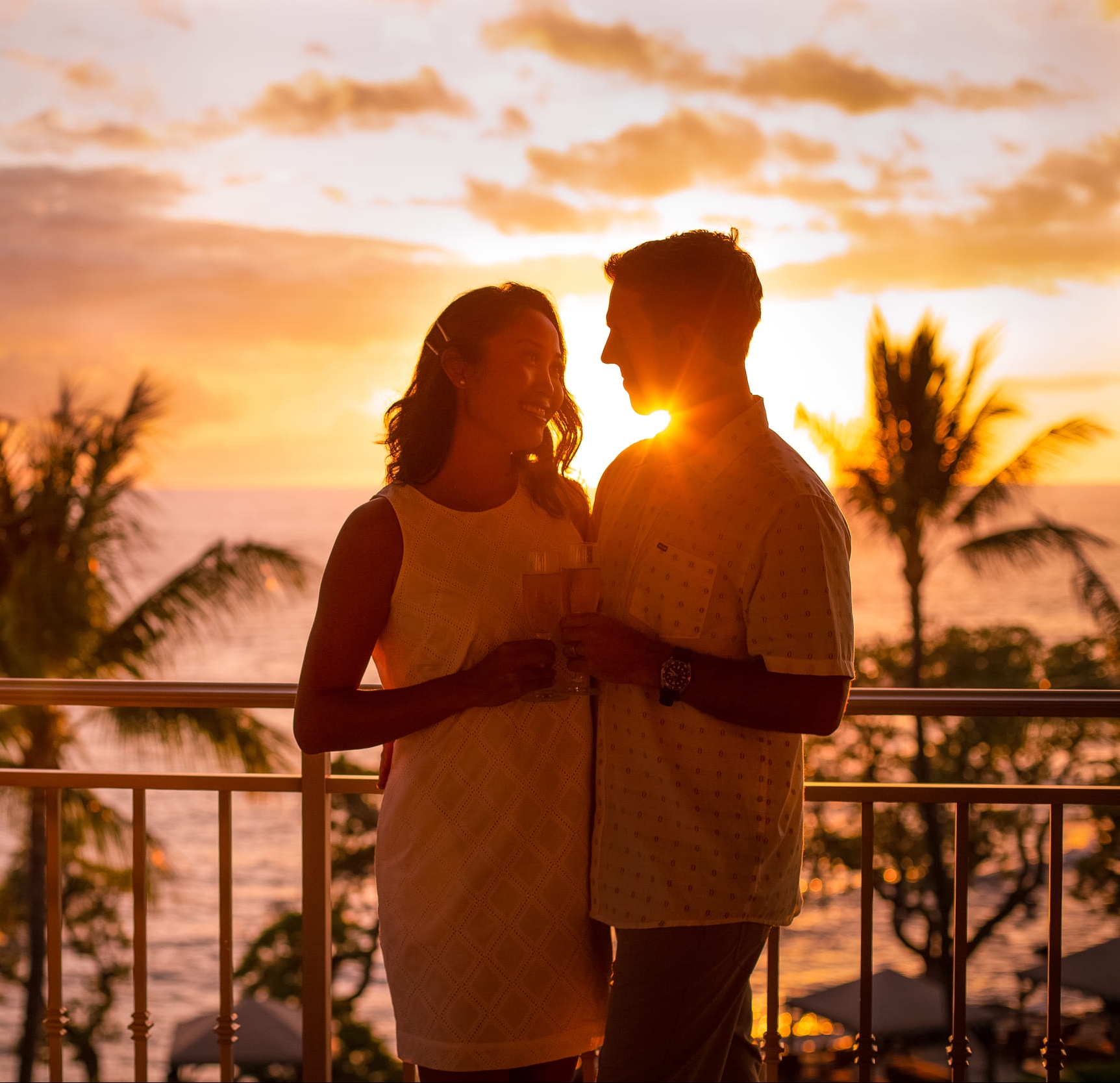a couple drinking in on a balcony at sunset