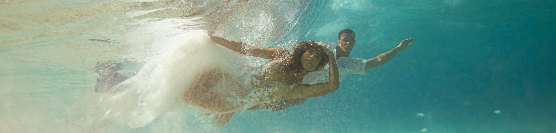 bride and groom swimming underwater in their wedding out fits