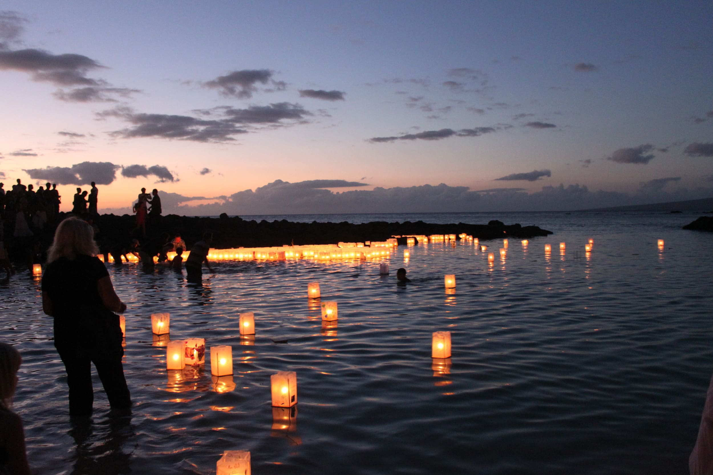people placing floating lanterns on the water