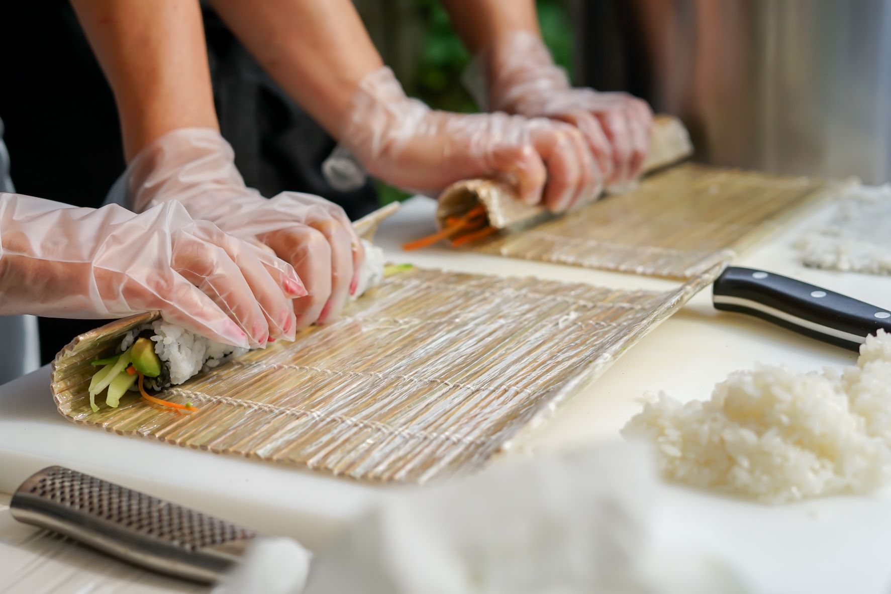Two people rolling sushi