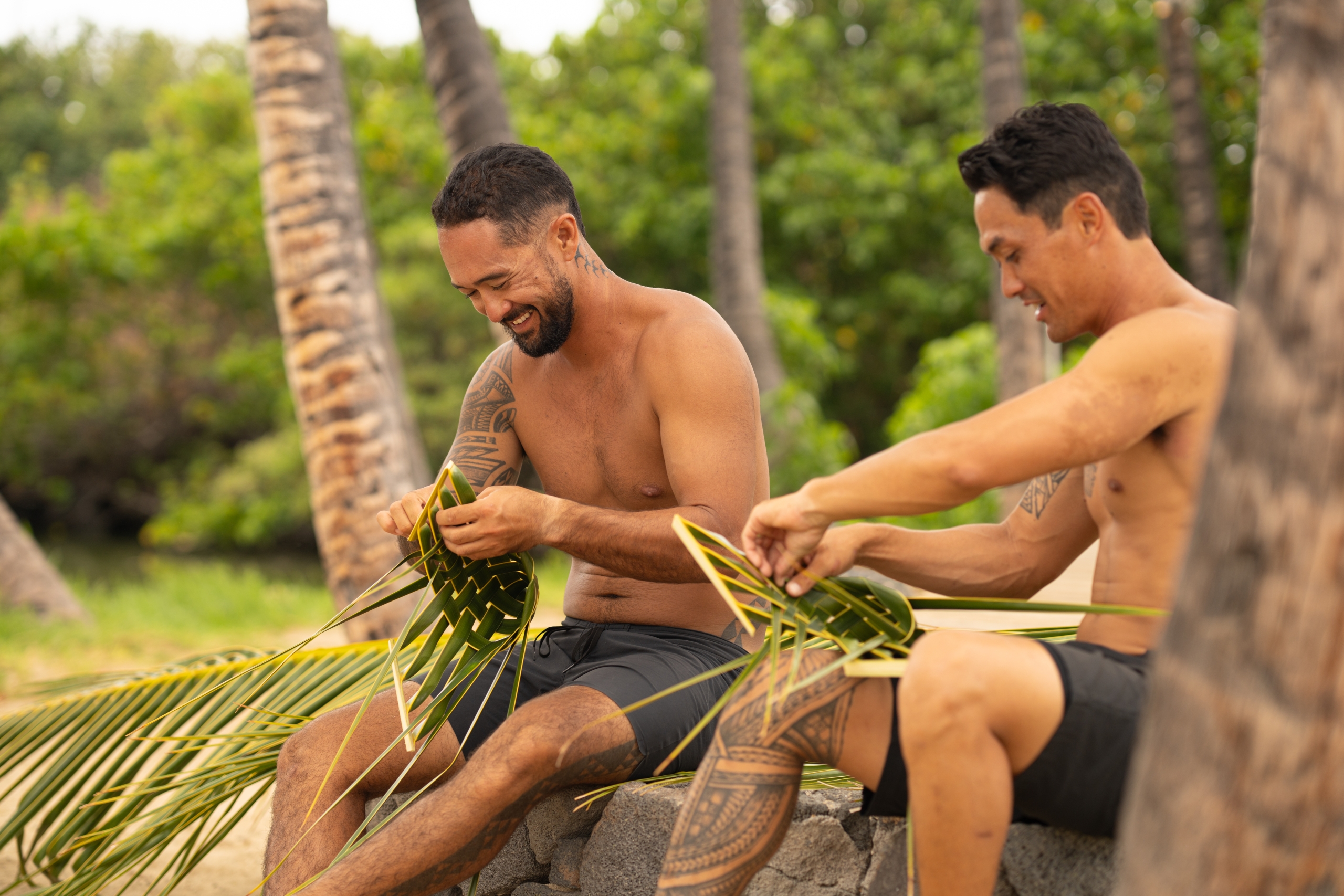 Two men sitting and weaving palm fronds