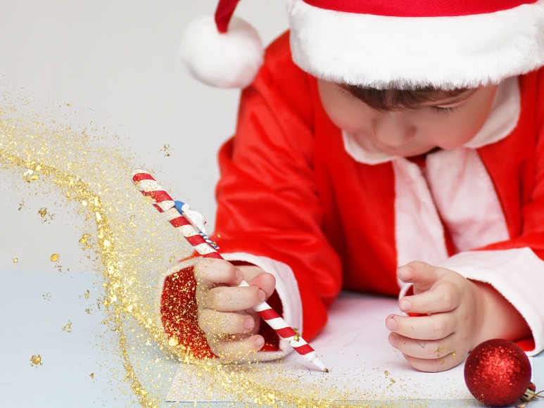 Little kid in santa outfit writing a letter