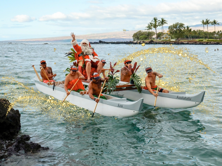Santa arriving on a canoe in the ocean with paddlers